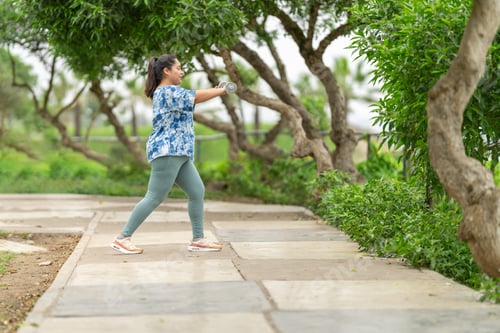 Preview: Overweight woman exercising with dumbbells in a park