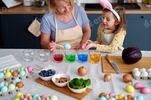 Preview: Granddaughter with grandmother dyeing Easter eggs on the table