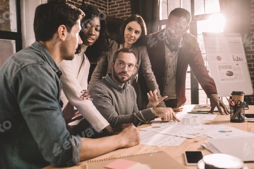 Preview: concentrated multiethnic group of colleagues working together on new project in modern loft office