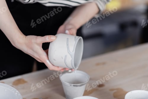 Preview: A young woman sitting in her studio and working with clay at her potters wheel