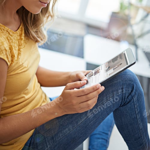 Preview: Shot of an attractive young woman chilling on her kitchen floor using a digital tablet