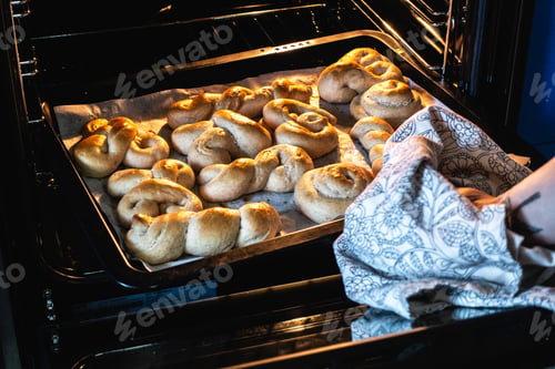 Preview: Woman taking out homemade baked dessert from oven