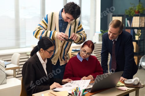 Preview: Multiethnic Team Collaborating in Office While Young Man Photographing Document