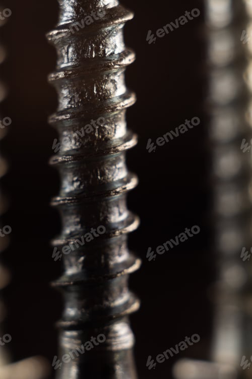 Preview: Vertical shot of different screws and bolts on a rough surface