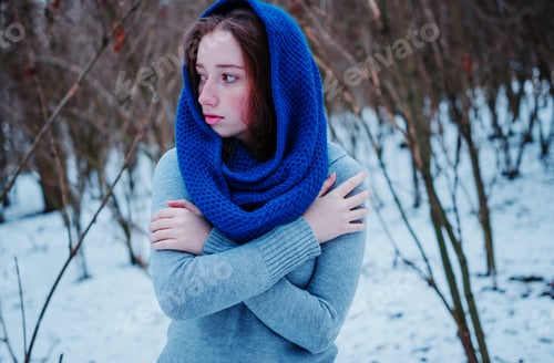 Preview: Portrait of young red hair girl with freckles wearing at blue knitted wool scarf in winter day.
