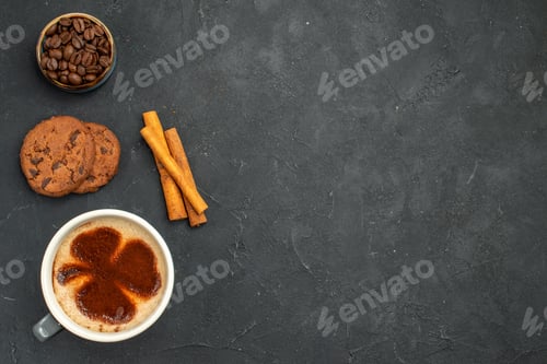 Preview: top view a cup of coffee bowl with coffee bean seeds cinnamon sticks biscuits on dark isolated