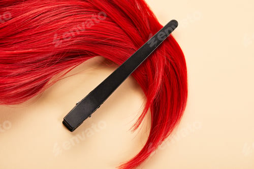 Preview: Top view of clip and colored red hair on beige background