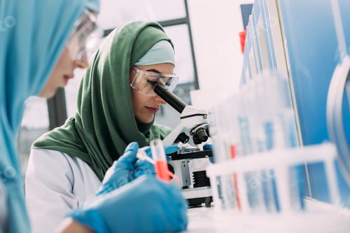 Preview: selective focus of female muslim scientist looking through microscope in chemical laboratory
