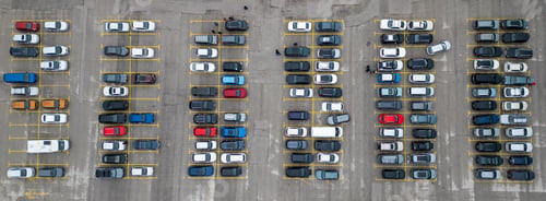 Preview: Busy parking lot filled with various vehicles during a cloudy day in an urban area