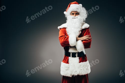 Preview: santa claus in costume standing with crossed arms isolated on grey background