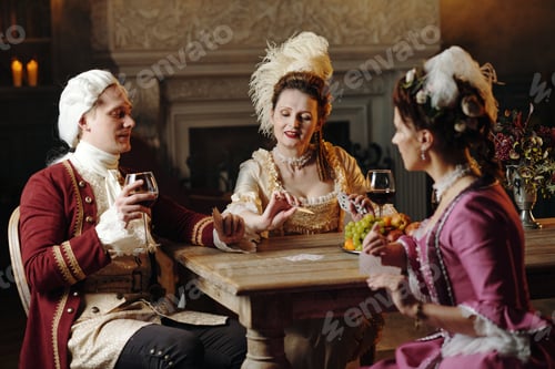 Preview: Caucasian Young Adults in Baroque Costumes Playing Cards and Drinking Wine
