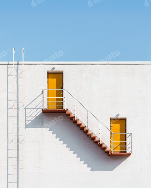 Aperçu: Architectural minimalism: Two yellow doors linked by a staircase against Helsinki's clear sky.