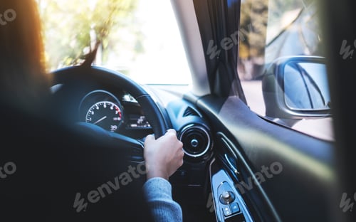 Preview: Closeup image of a woman holding steering wheel while driving a car on the road