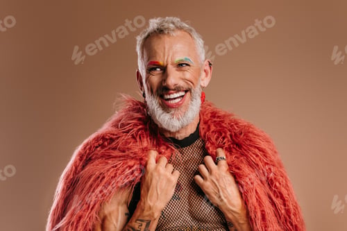Preview: Happy mature gay man with rainbow colored eyebrows wearing fluffy coat against brown background