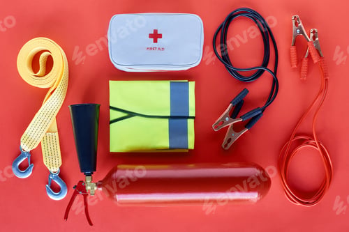 Preview: top view of fire extinguisher, first aid kit and jump start cables on red background