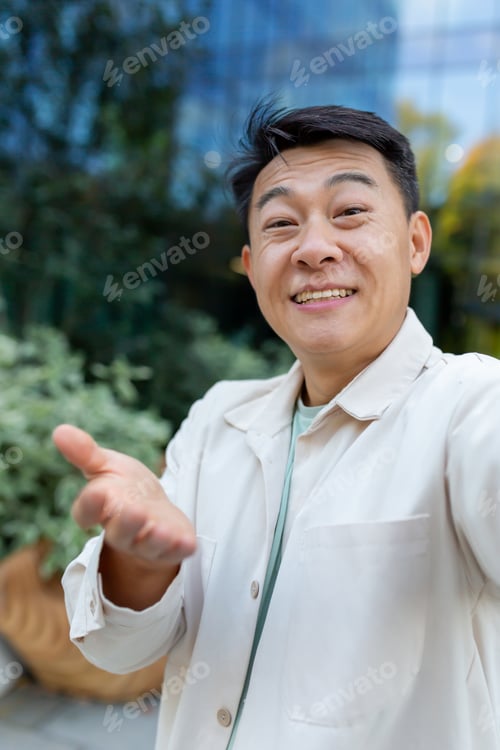 Preview: Asian programmer talking on video call using app on phone, view camera man waving and talking