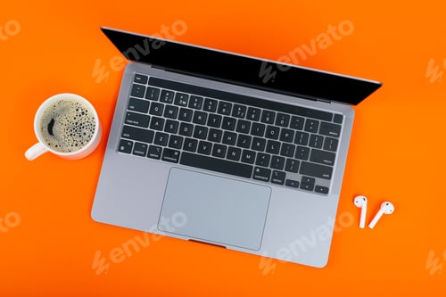 Preview: Laptop with blank screen, cup of coffee and wireless headphones on orange background