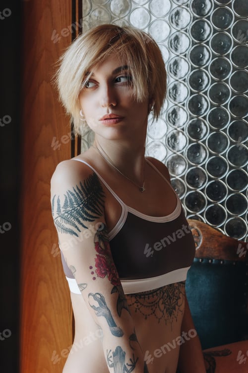 Preview: beautiful tattooed woman in underwear looking away indoors