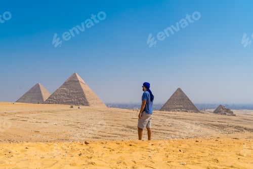 Preview: A young man in a blue turban walking next to the Pyramids of Giza