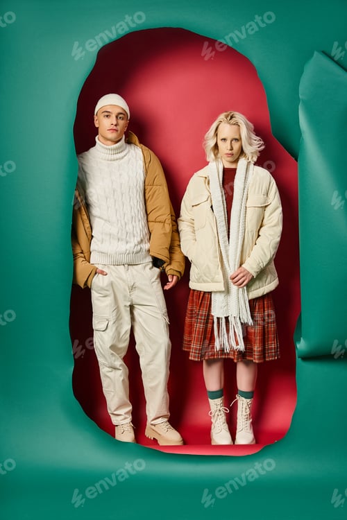 Preview: young man posing with hand in pocket near stylish woman on torn turquoise and red background