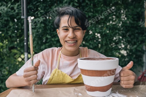 Preview: Teenage girl with brush in hand and ceramic pot she painted