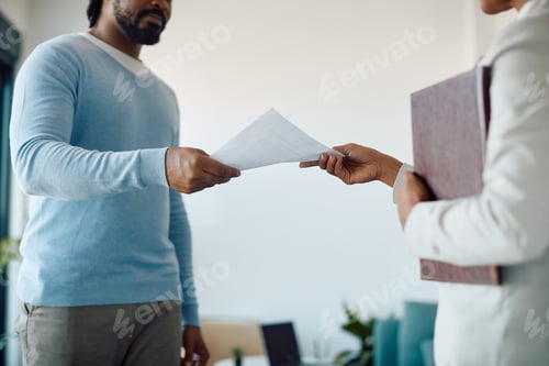 Preview: Close-up of African American candidate giving his resume while applying for job in the office.