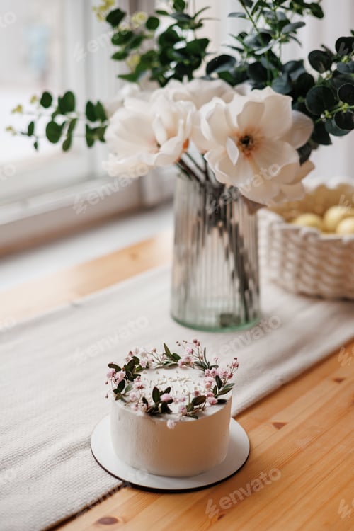 Preview: Top view of rustic style white cream cake decorated with fresh flowers, greens and happy birthday in