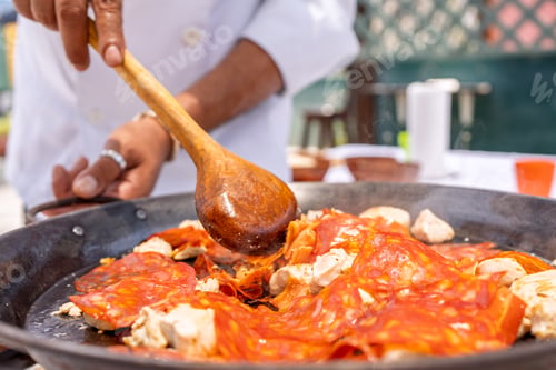 Preview: Chef preparing paella with chicken and chorizo outdoors