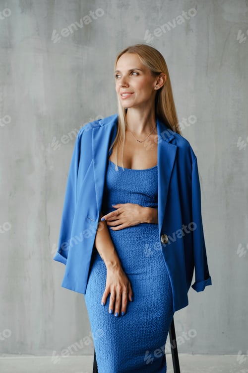 Preview: Strong woman in elegant blue outfit posing in minimalistic room