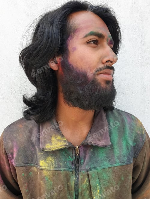 Preview: Close up portrait of young man covered with multicolor holi color powder