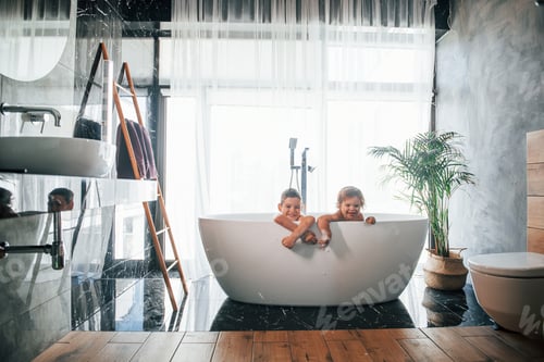 Preview: Two kids having fun and washing themselves in the bath at home. Posing for a camera