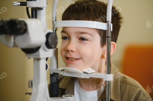 Preview: Boy undergoing eyesight examination with phoropter in ophthalmology clinic
