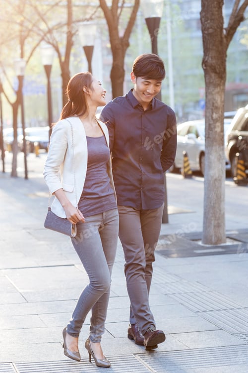 Preview: Young couple holding hands walking on sidewalk