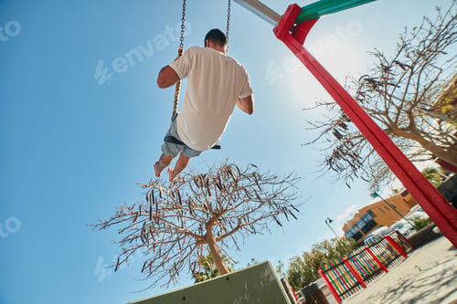 Preview: Man swinging on playground in sunlight