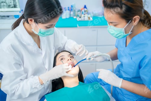 Preview: Asian young dentist wearing face mask use medical instruments for oral care at dentel clinic.
