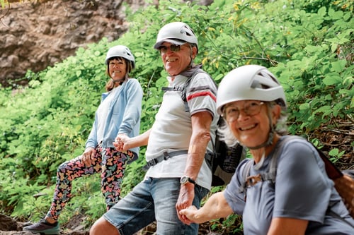Preview: Group of happy senior people enjoying a trekking day in mountain wearing protective helmets