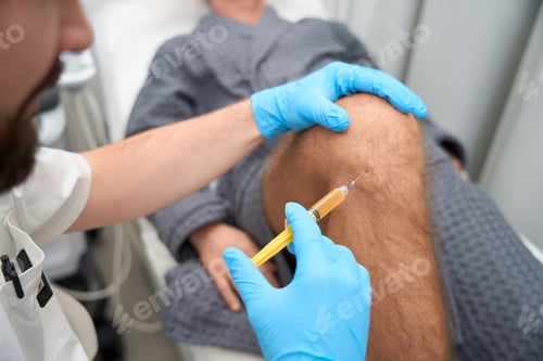 Preview: Experienced doctor taking a biopsy sample from man knee