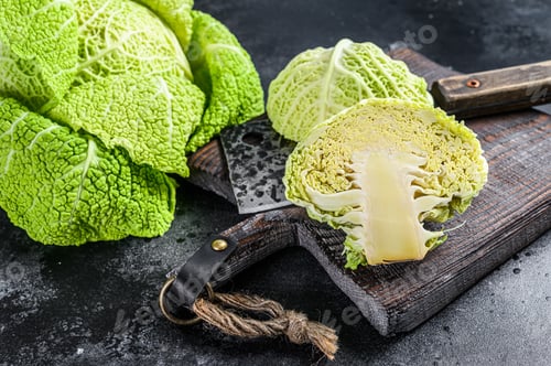 Preview: Cut Fresh healthy savoy cabbage on cutting board. Black background. Top view
