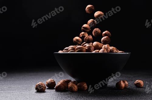 Preview: Falling hazelnuts on black background with copy space