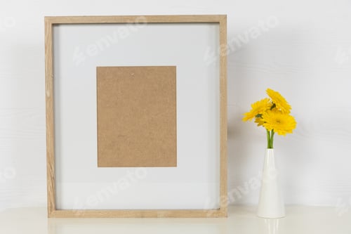 Preview: View of a picture frame, with yellow tulips placed in a glass vase on plain white background