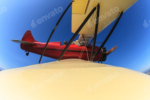 Preview: Elevated wide angle view of bi-plane wing and pilot in flight