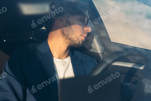 Preview: Tired business man falling asleep sitting inside her car seen through windshield