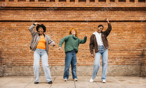 Preview: Three young women dancing in front of brick wall