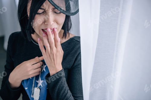 Preview: crying woman holding tag dog and folded american flag at home
