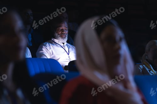 Preview: old businessman looking at digital tablet while sitting in the auditorium