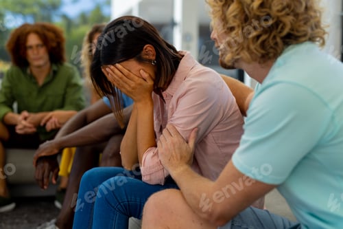Preview: Group of diverse people sitting on sofa, talking and crying in group therapy session