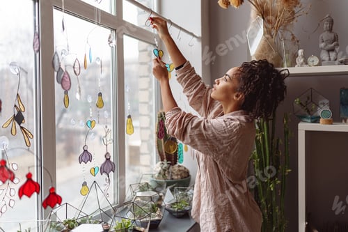 Preview: Woman holding handmade glass decoration in the form of heart standing in home decor studio