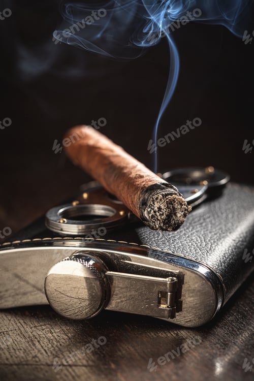 Preview: Burning cigar on luxury leather hip-flask on black background