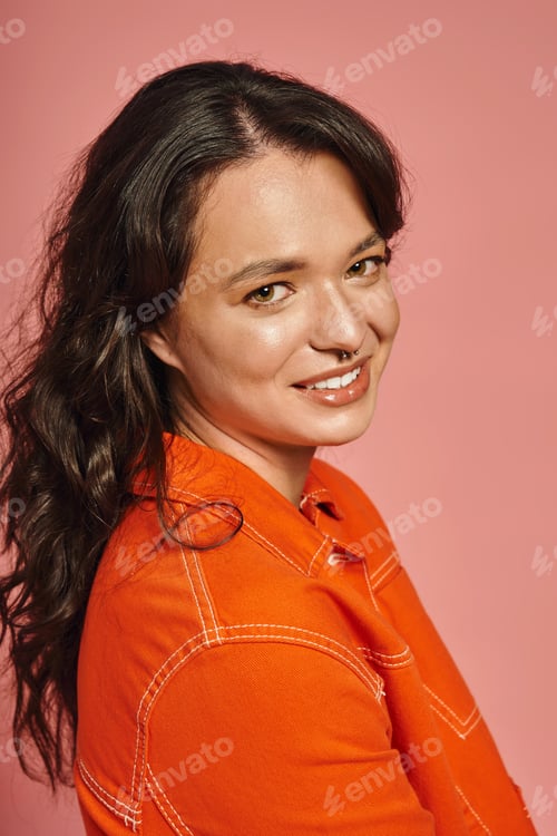 Preview: Young stylish woman showcases vibrant fashion sense against a playful pink background