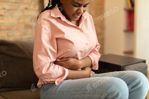 Preview: Sad black woman in casual clothes suffering from menstrual pain, feeling sick to her stomach